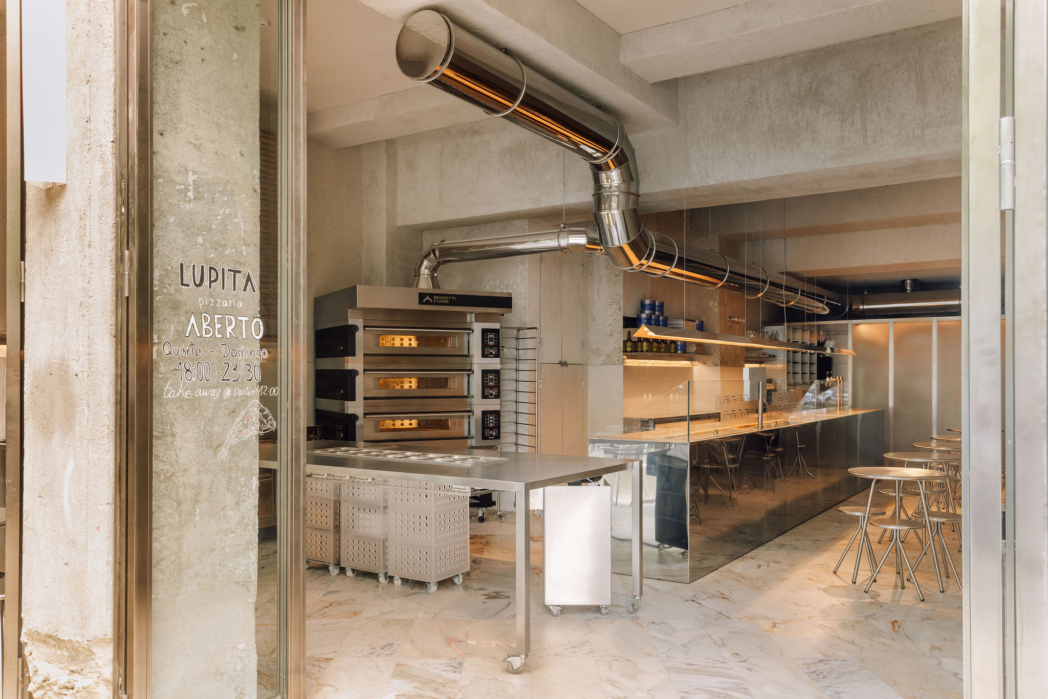 Lupita Alvalade by XXXI.studio with an open pizza-making area facing the street in Lisbon, Portugal