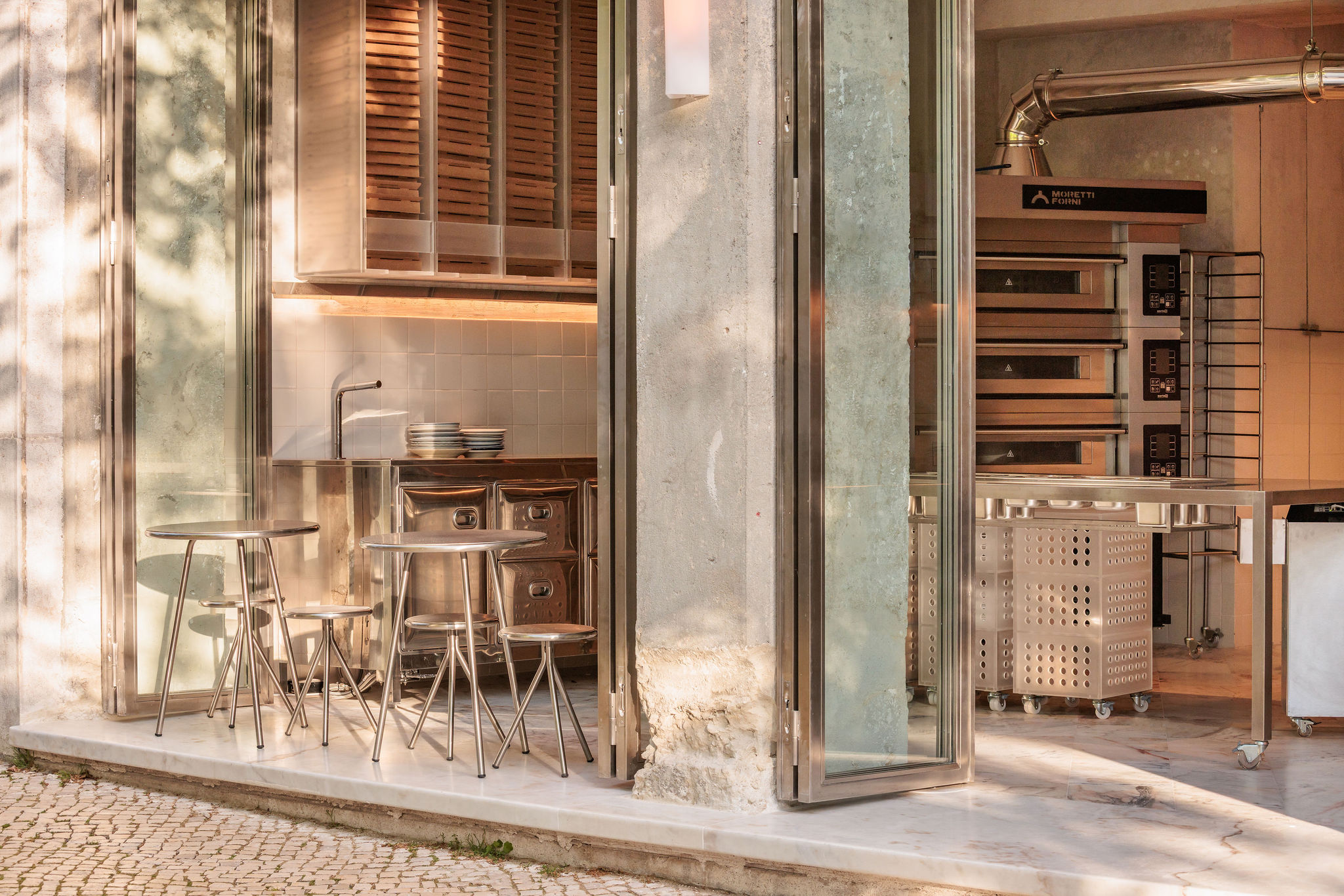 Lupita Alvalade by XXXI.studio with an open pizza-making area facing the street in Lisbon, Portugal